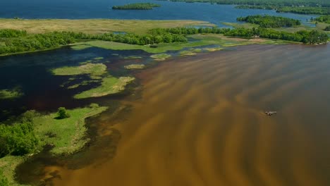 Upward-panning-drone-shot-of-two-beautiful-shallow-lakes-with-sand-ripples-showing-on-a-bright-beautiful-sunny-day-in-North-Bay,-Canada