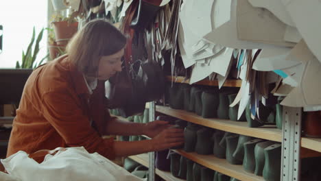 woman taking last from shelf in shoemaking workshop