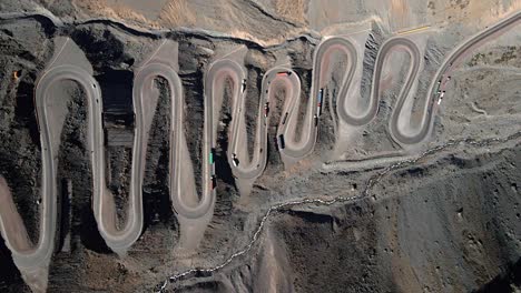 Aerial-overhead-truck-right-view-of-the-Cuesta-Caracoles-road,-border-between-Chile-and-Argentina,-cars-passing-through-the-curves-of-the-route