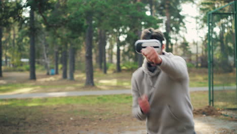 man wearing vr headset boxing in a park