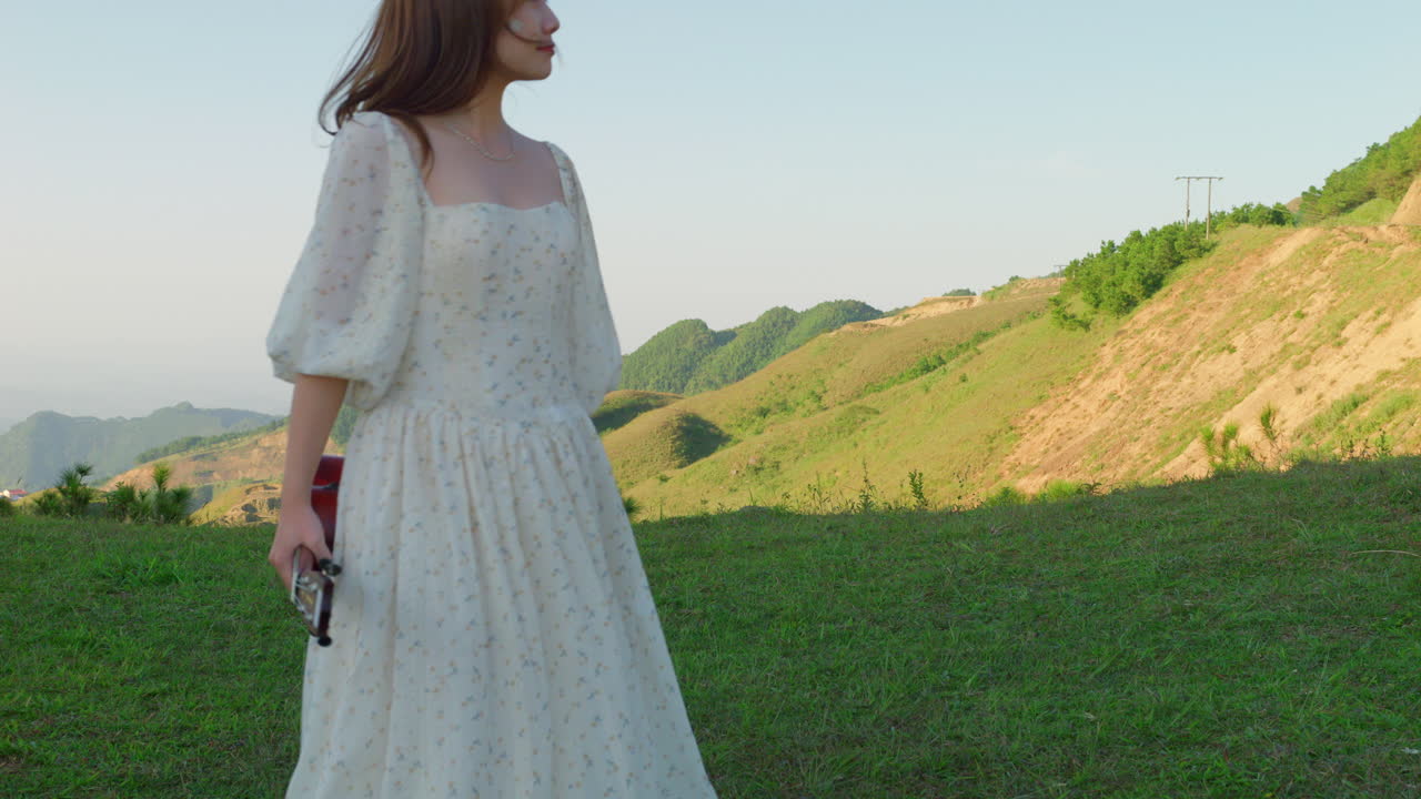 barefoot musician walking in slow motion and dancing wearing elegant white dress holding a guitar in her hand