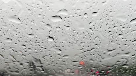 fuertes lluvias cayendo sobre el parabrisas y luces rojas borrosas del tráfico de automóviles en el fondo con limpiaparabrisas limpiando el parabrisas de las gotas de lluvia