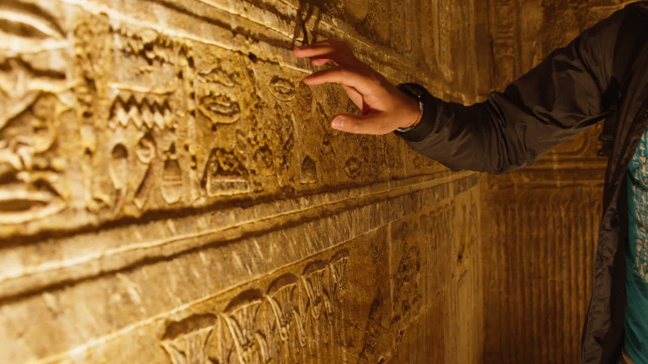 Touching ancient wall carvings at Dendera temple, warm light, curious and respectful mood