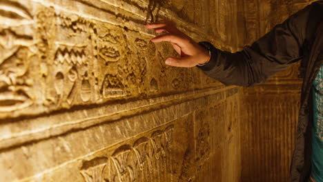 touching ancient wall carvings at dendera temple, warm light, curious and respectful mood