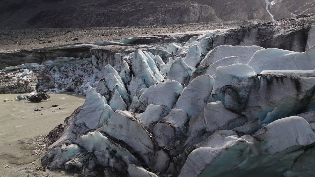 glaciar de montaña más antiguo derritiéndose debido al calentamiento global, glaciar cubierto de suciedad y escombros, lago glaciar fangoso, primer plano aéreo