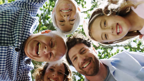 multi-generation family forming huddle in the park