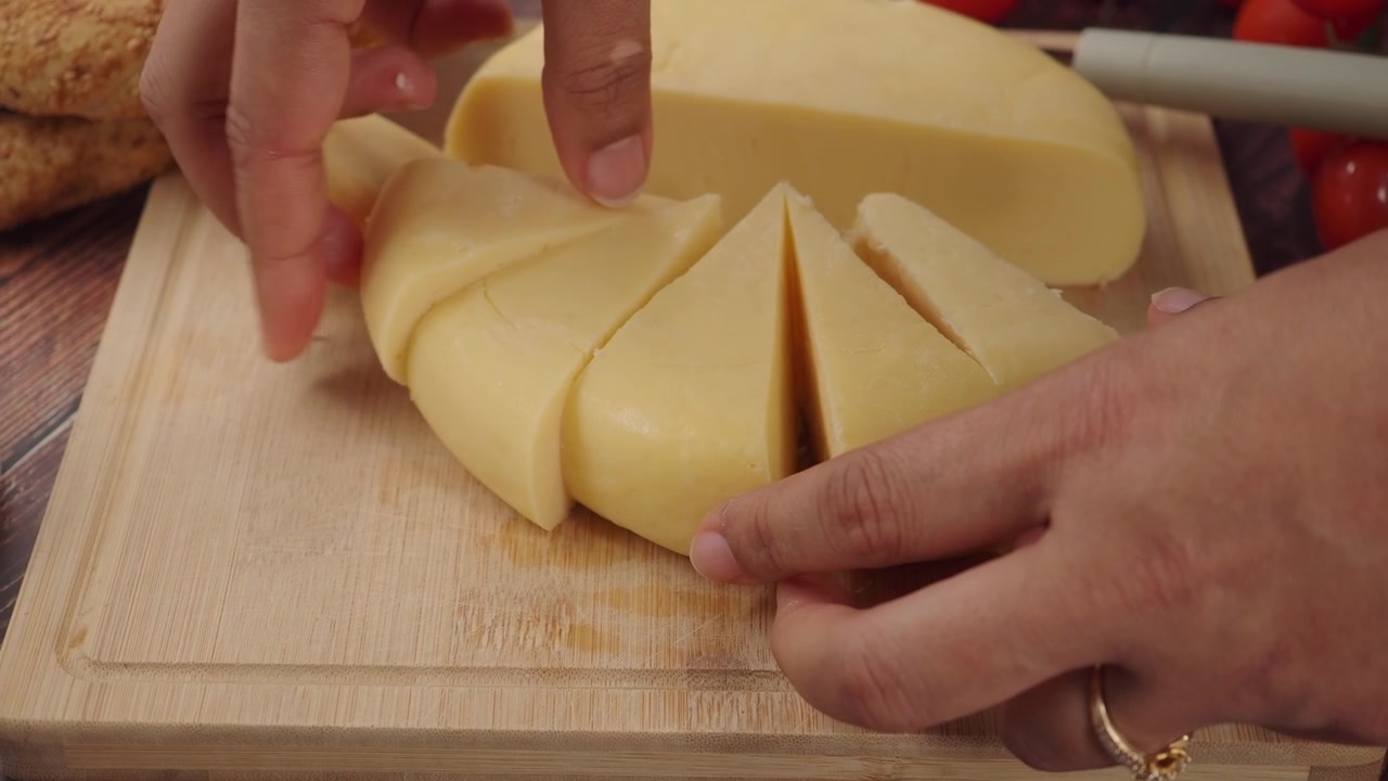 Persona che dispone fette di formaggio fresco su un tagliere di legno