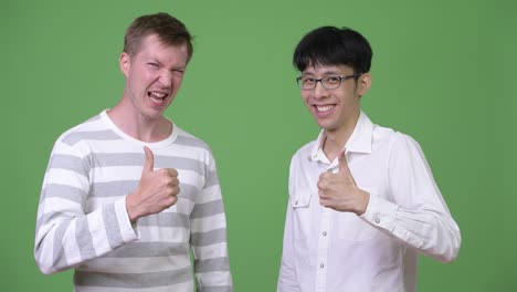 two happy young multi-ethnic businessmen giving thumbs up together