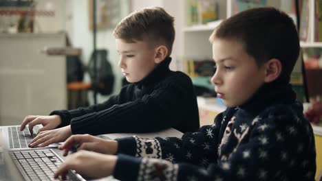 Footage-of-two-little-boys-trying-to-type-something,-learning-how-to-use-laptops.-Alternative-programming-education-for-children.