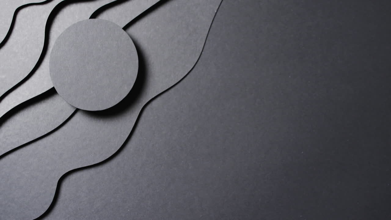 Video of close up of circle of black paper on waves cut out and copy space on black background