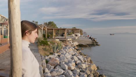 closeup of a woman standing by the sea and gazing upon during golden hour