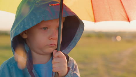 child under downpour with furrowed brows little boy solitude under umbrella accentuated by