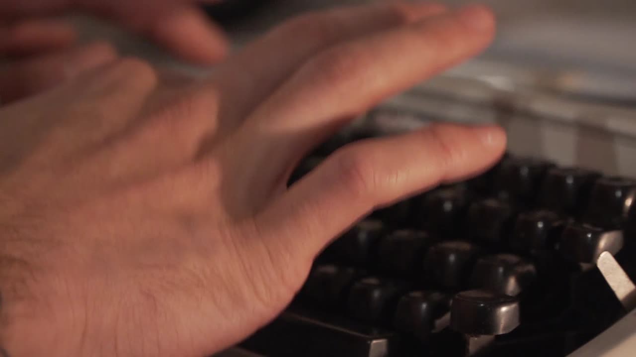 Close up of mans fingers typing on a typewriter