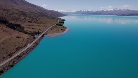 Aerial-Lake-Pukaki-Fliegt-Entlang-Der-Straße-Mit-Blick-Auf-Den-Schneebedeckten-Mount-Cook