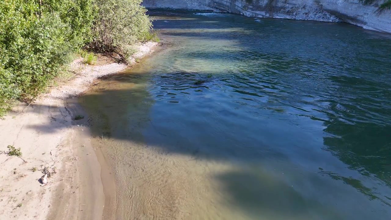 Droneoptagelse fra høj vinkel fanger en rolig flod, der strømmer forbi en sandbanke i Piemonte.