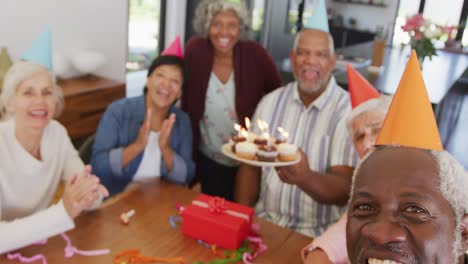 Portrait-of-happy-senior-diverse-people-at-birthday-party-with-cake-and-gifts-at-retirement-home