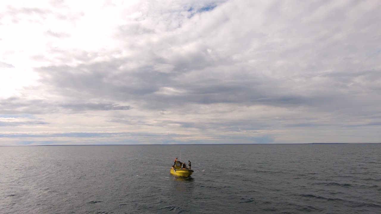 pequeño barco de pesca flotando en medio del océano en un día nublado y tranquilo - plano aéreo amplio