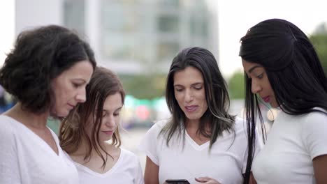 Cheerful-women-standing-in-circle-and-using-smartphones