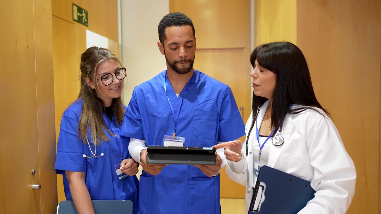 Professionisti sanitari che discutono i dati del paziente su tablet nel corridoio dell'ospedale