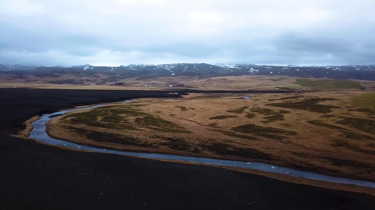 Aerial landscape view of a river flowing between Iceland highlands and volcanic black sand
