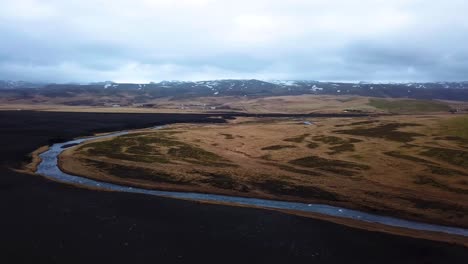 aerial landscape view of a river flowing between iceland highlands and volcanic black sand