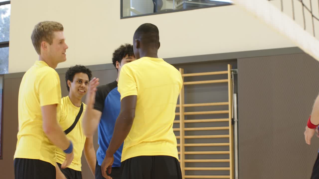 Diverse male players in yellow shirts sitting on court after talk, grabbing duffel, bottle, walking
