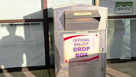 woman votes by droping mail-in ballot letter in slot at voting booth with offical ballot drop box sign for democratic government election in presidential race