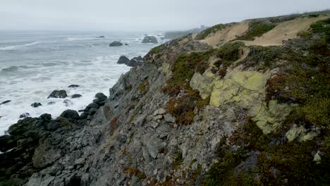 Vista-Aérea-Sobre-Los-Acantilados-Marinos-Mientras-Las-Olas-Chocan-En-La-Playa-De-La-Roca-De-La-Cabra,-Bahía-Bodega-California