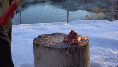 Person-using-axe-to-chop-beef-bones-out-in-the-snow