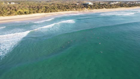 Surfistas-Acostados-En-Tablas-De-Surf-Flotando-En-El-Mar-Azul-En-La-Playa-Coolum,-Costa-Del-Sol,-Qld,-Australia