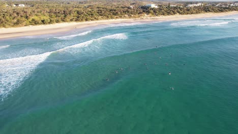 surfers lying on surfboards floating in the blue sea in coolum beach, sunshine coast, qld, australia