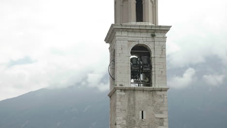 close-up handheld shot of bells tolling in a church tower with misty mountains in background