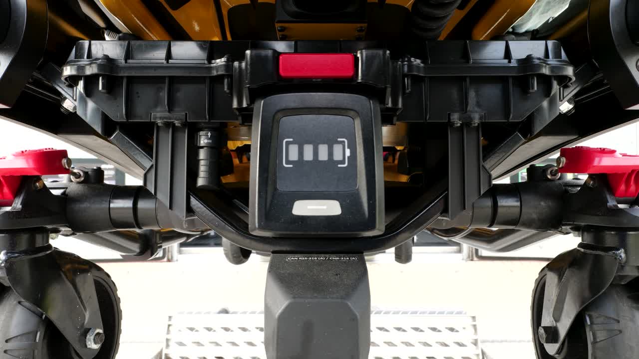 Modulo batteria della barella motorizzata per ambulanza visibile mentre il carrello si abbassa e si allontana dal vano di carico dell'ambulanza — ripresa ravvicinata posteriore con profondità di campo ridotta.