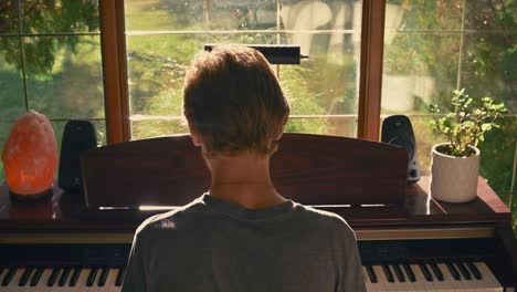 boy playing piano by a window - jib shot