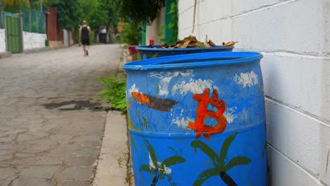 toma completa, un tambor azul con un logo rojo de bitcoin en la playa de bitcoin en el salvador, méxico, una persona caminando en el fondo