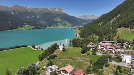 aerial de uma área residencial e um lago tranquilo perto de campanile di curon venosta vecchia, no tirol do sul, itália