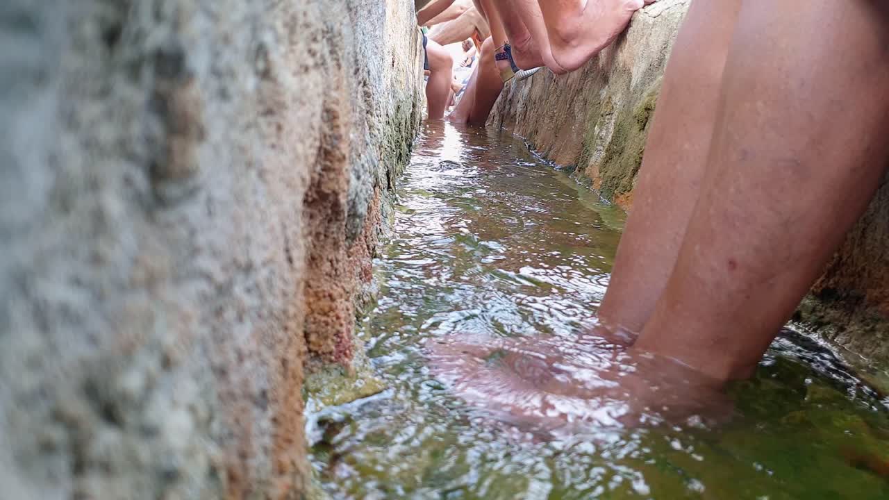 los turistas se relajan sumergiendo los pies en el canal termal que fluye agua caliente, bagno vignoni.