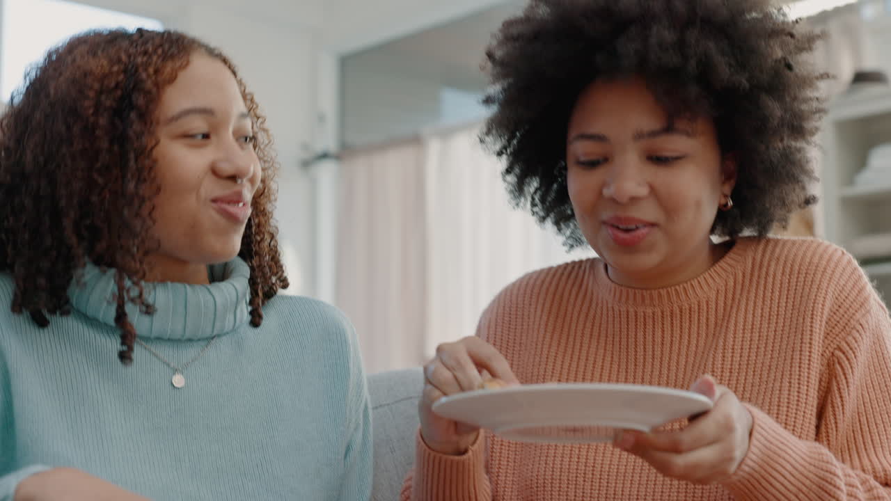 Women friends eating pizza on sofa in their home