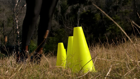 Low-section-of-woman-running-through-training-cones