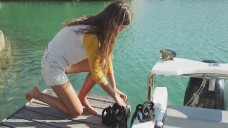 side view of a teenage caucasian girl untying a rope on the boat harbor side