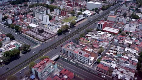 view of the busy calzada de tlalpan where it intersects with the axis 6 calzada primero de mayo in colonial nativitas, several vehicles can be seen on the avenue and many housing constructions