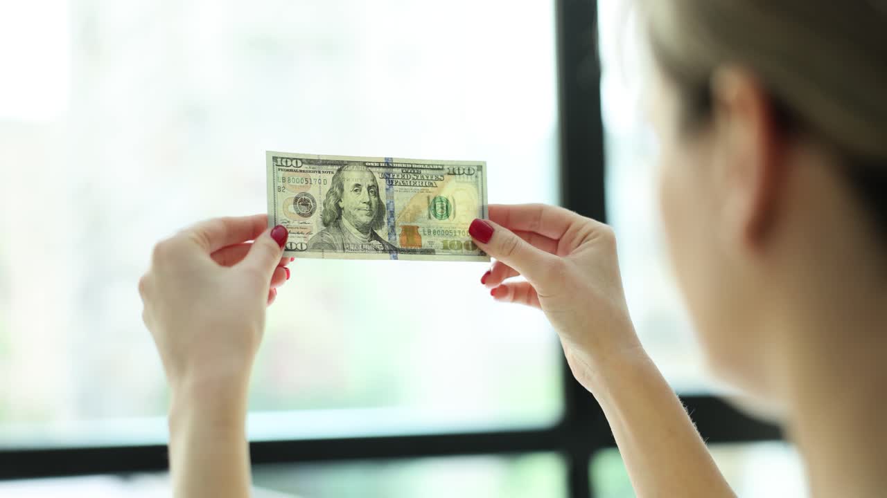 Woman holding a hundred dollar bill