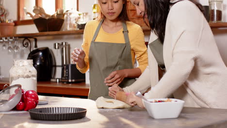 multiracial young woman and grandmother rolling dough together in cozy kitchen, at home