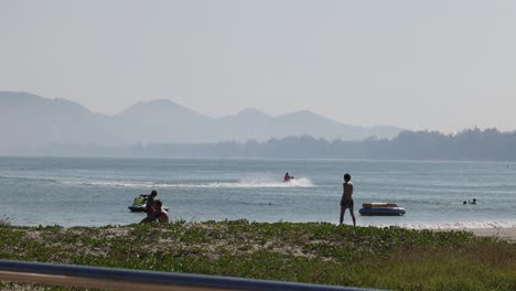 jet ski rider cruising past beach observers.