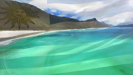 composición digital de la bandera uruguaya ondeando contra la vista aérea de las olas en el mar
