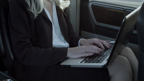 gray haired woman working on laptop in car