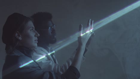 multiethnic man and woman touching flat sheet of laser light