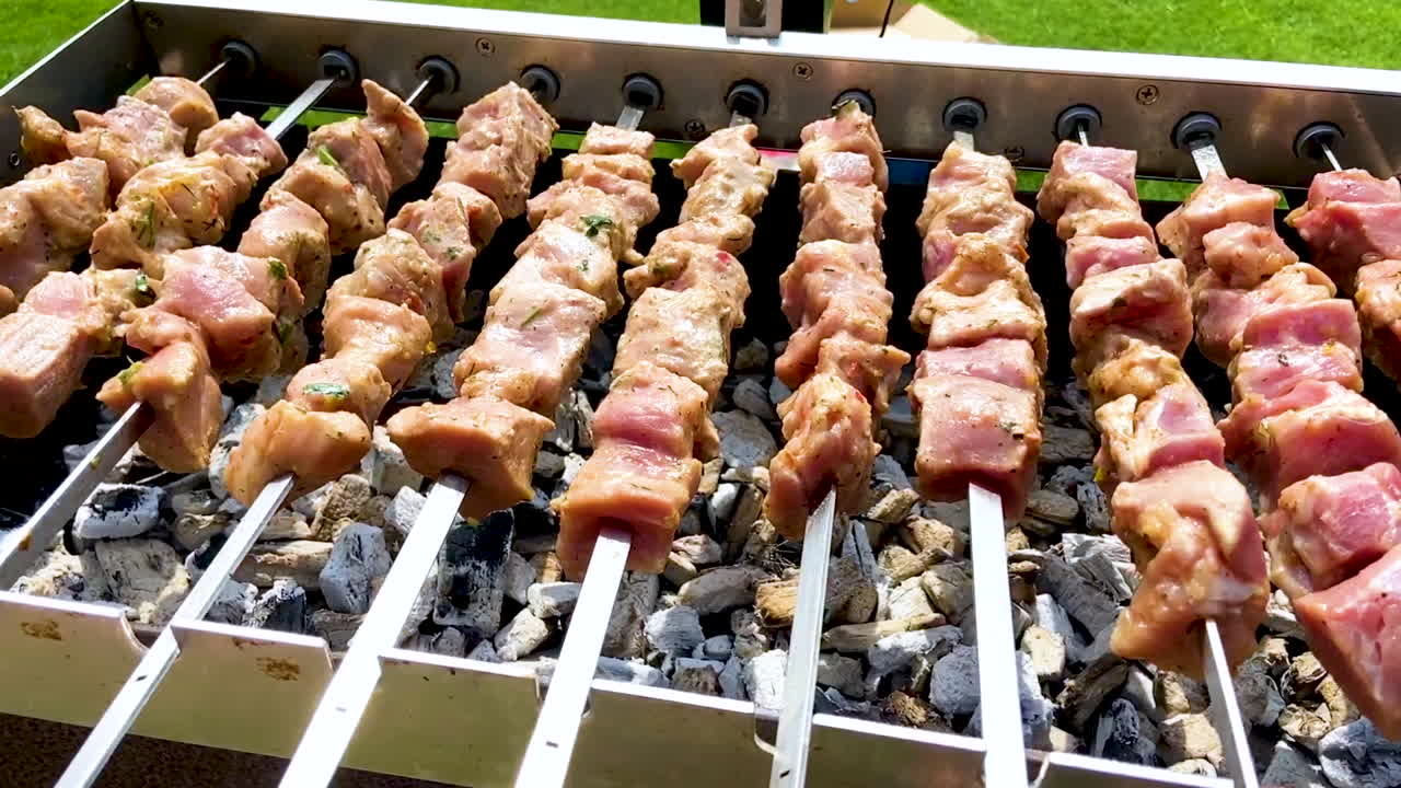 Primo piano di spiedini Shashlik che cuociono su carbonella ardente su una griglia rotante