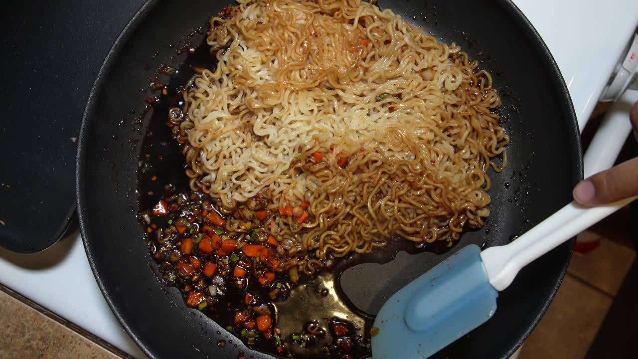 mezclando fideos ramen en la salsa con una espátula