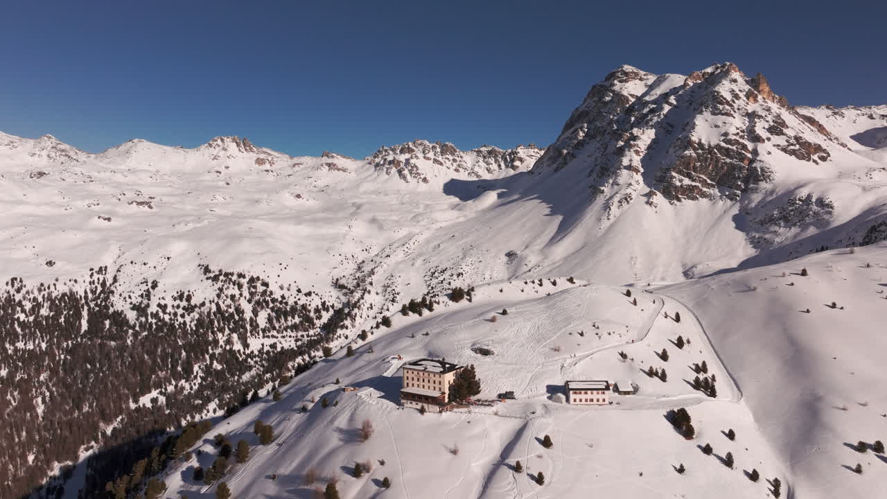 Drone aerial of Hotel Weisshorn, Switzerland. Iconic alpine hotel surrounded by snowy peaks and forests, offering breathtaking mountain scenery for travel, tourism and cinematic stock footage